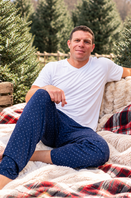 Man wearing navy Midnight Dot bamboo pajamas for Hanukkah and Christmas, featuring a classic white dot print and comfortable holiday sleepwear design