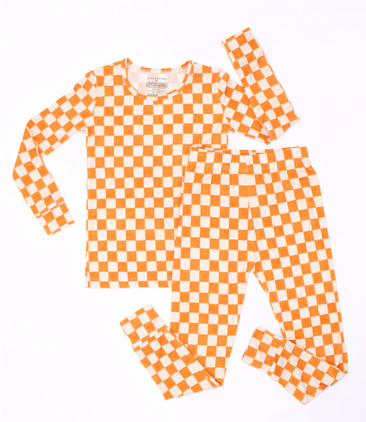 Orange and ivory Pumpkin Patch checkered big kids pajamas arranged in a flat lay, showcasing the long-sleeve top and matching pants