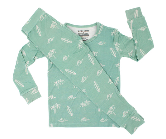 Flat lay of the Surfside Dreams kids bamboo pajama set by Shae & Palmer featuring a soft coastal print with surfboards, palm trees, and ocean-inspired details.