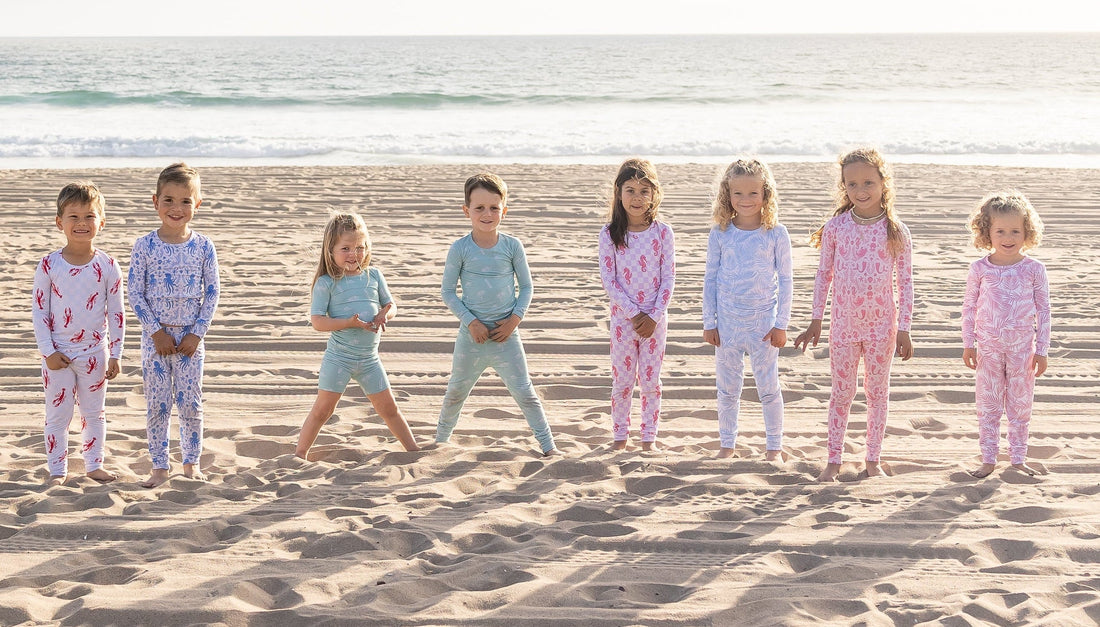 Young child in soft pastel bamboo pajamas playing calmly on the beach, sun-warmed sand, relaxed coastal setting