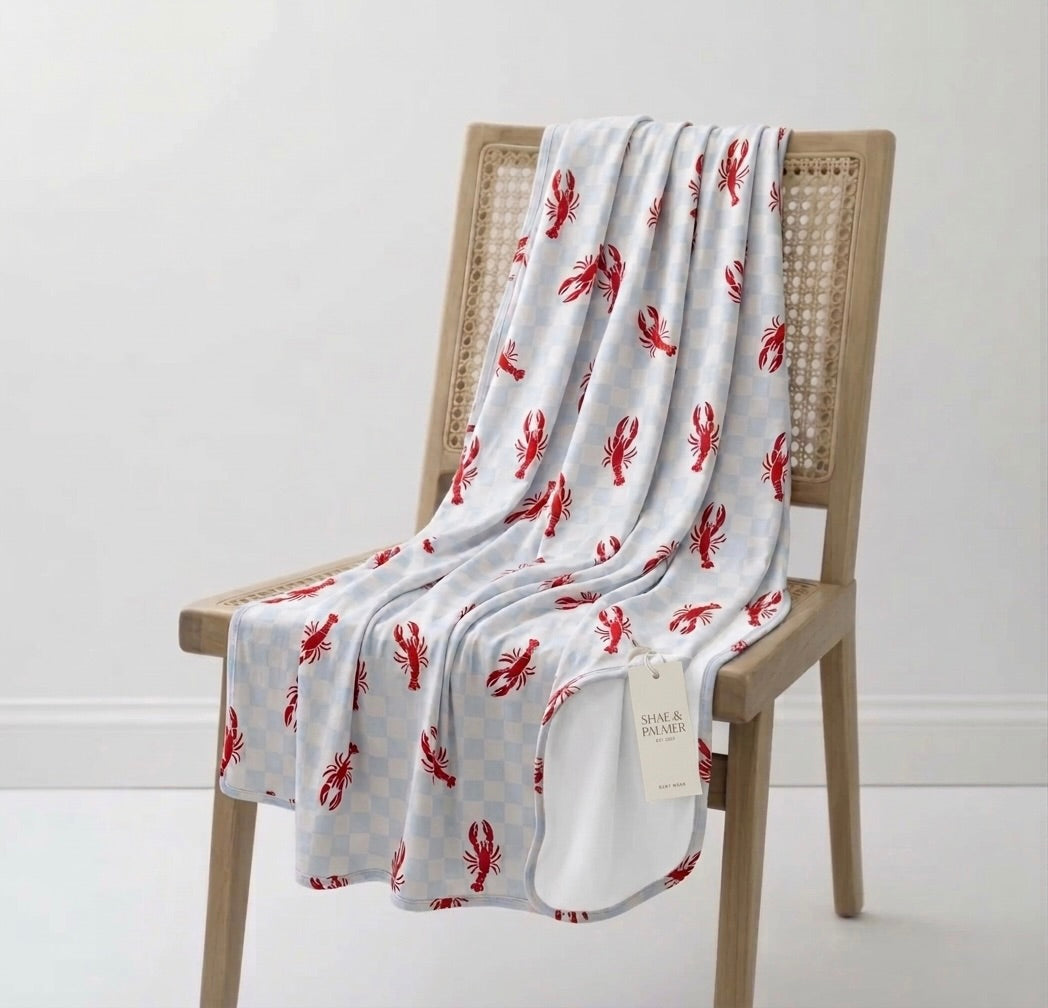 Close-up of Lobster Splash bamboo blanket showing blue checkered fabric with red lobster coastal design detail