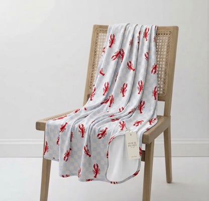 Close-up of Lobster Splash bamboo blanket showing blue checkered fabric with red lobster coastal design detail