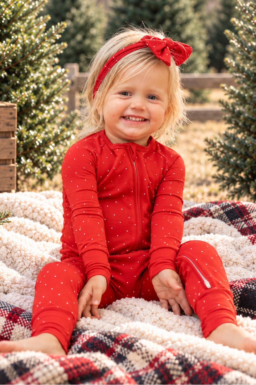 Baby wearing Ruby Dot red bamboo pajamas with a delicate white dot print, soft cozy Christmas holiday sleepwear for infants