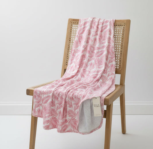 Baby wrapped in Cali Coastal Pink bamboo blanket by Shae & Palmer, soft breathable temperature-regulating fabric with palm print