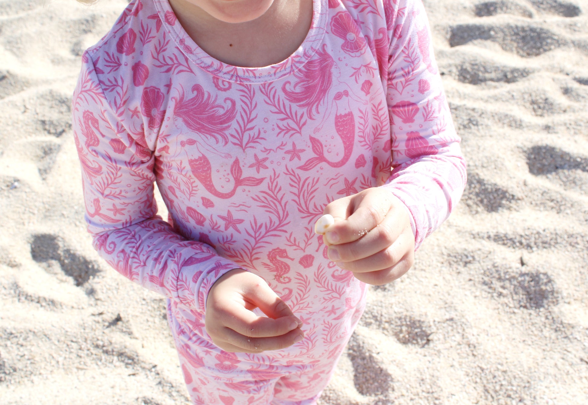 Coastal-inspired toddler pajama set with whimsical mermaids and seashells in neutral blush tones.