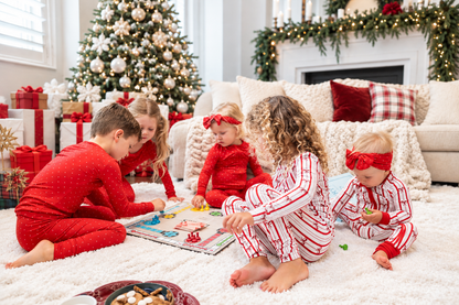 Family Christmas matching pajamas gathered together for a cozy holiday game night by the Christmas tree