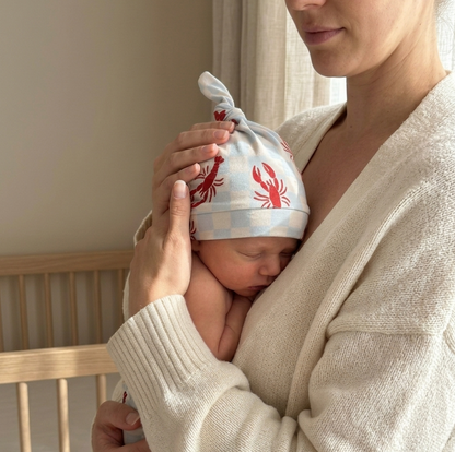 Newborn wearing Lobster Splash Blue bamboo baby hat, lightweight and temperature-regulating for cozy comfort