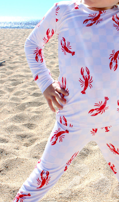 Close-up of Lobster Splash toddler pajamas showing blue checkered fabric with red lobster coastal print detail
