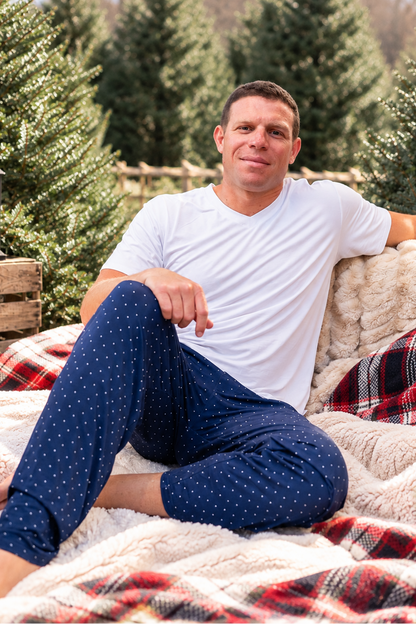 Man wearing navy Midnight Dot bamboo pajamas for Hanukkah and Christmas, featuring a classic white dot print and comfortable holiday sleepwear design