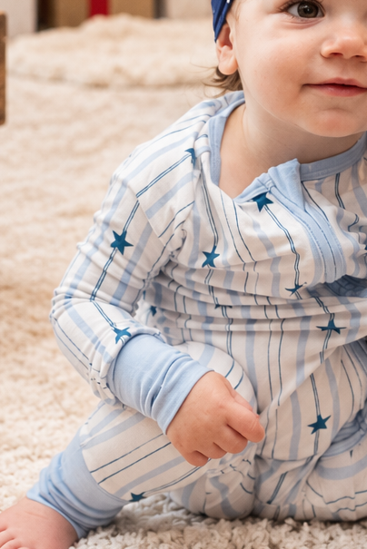 Close-up of baby wearing North Star bamboo pajamas featuring soft blue stripes and navy star print