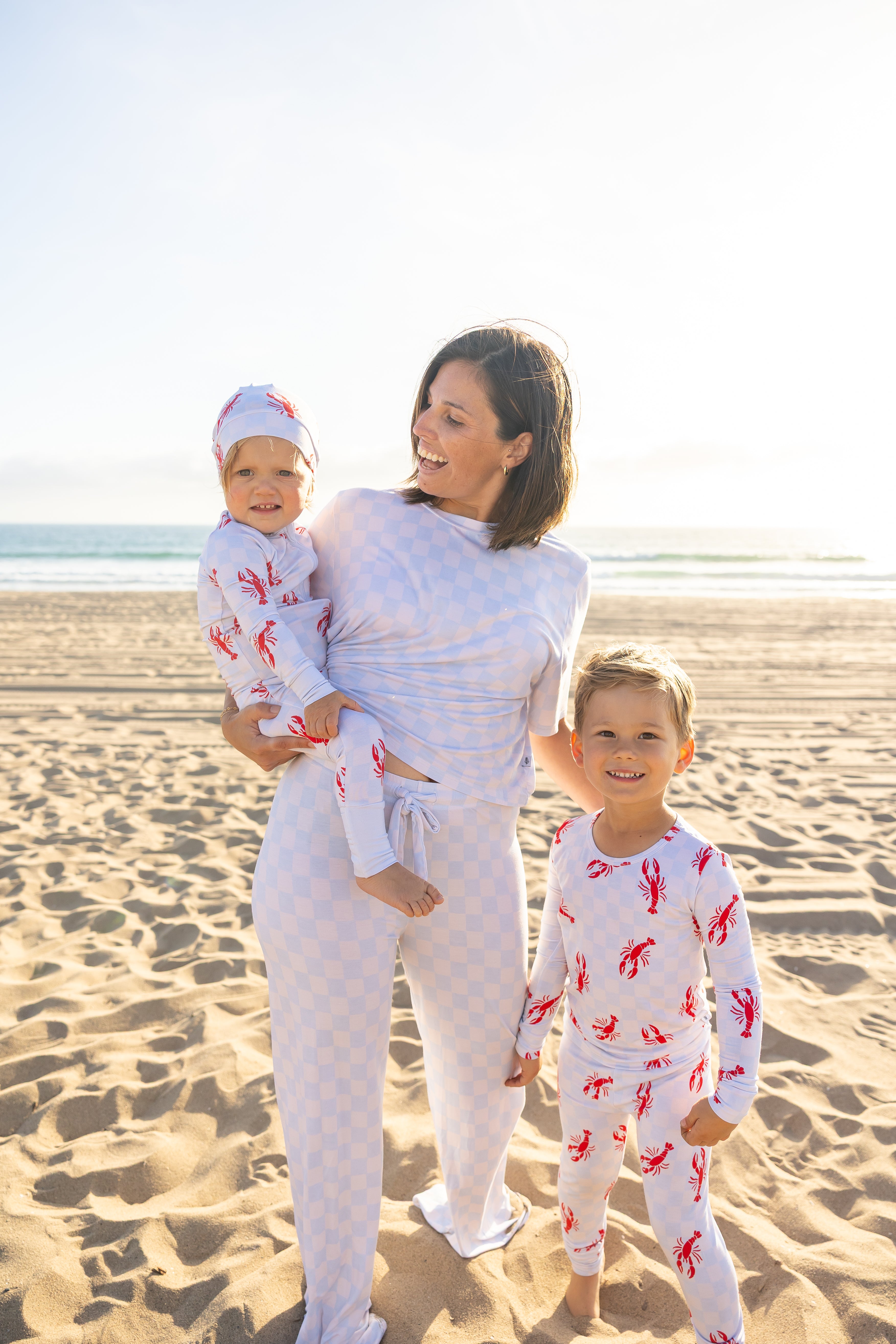 Matching Lobster Splash bamboo pajamas for mom, baby, and kids featuring red lobster print on a soft blue checkered design