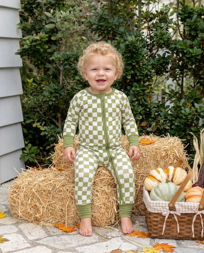 Baby wearing Orchard Checkered bamboo pajamas in a soft olive green and ivory checkered print during a cozy fall moment.