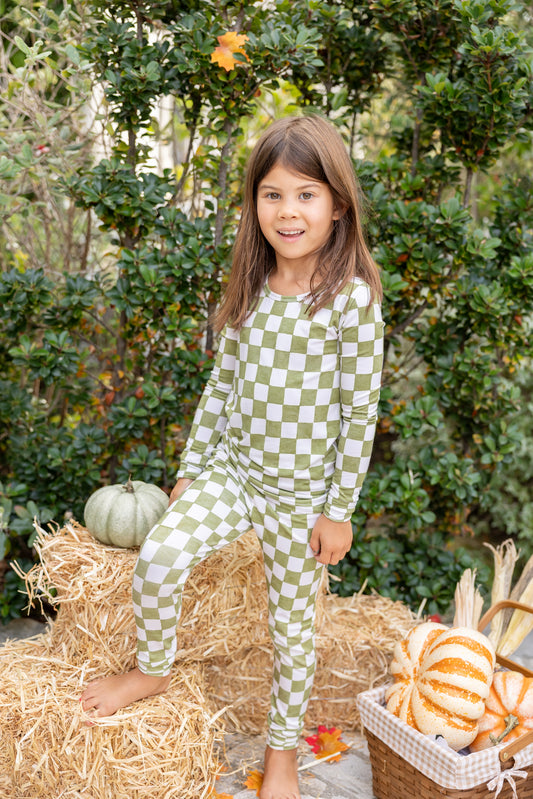Big kids wearing Orchard Checkered bamboo pajamas in an olive green and ivory checkered print during a cozy fall moment.