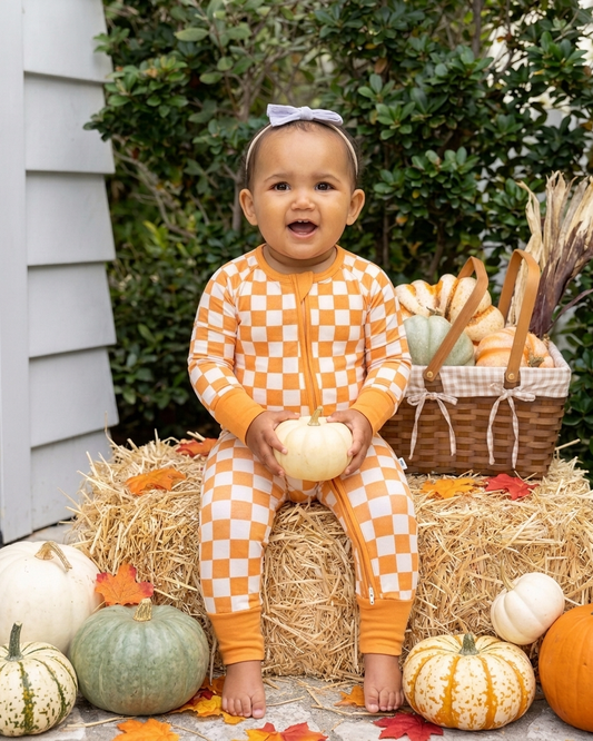 baby wearing Pumpkin Patch bamboo pajamas in an orange and ivory checkered fall print.