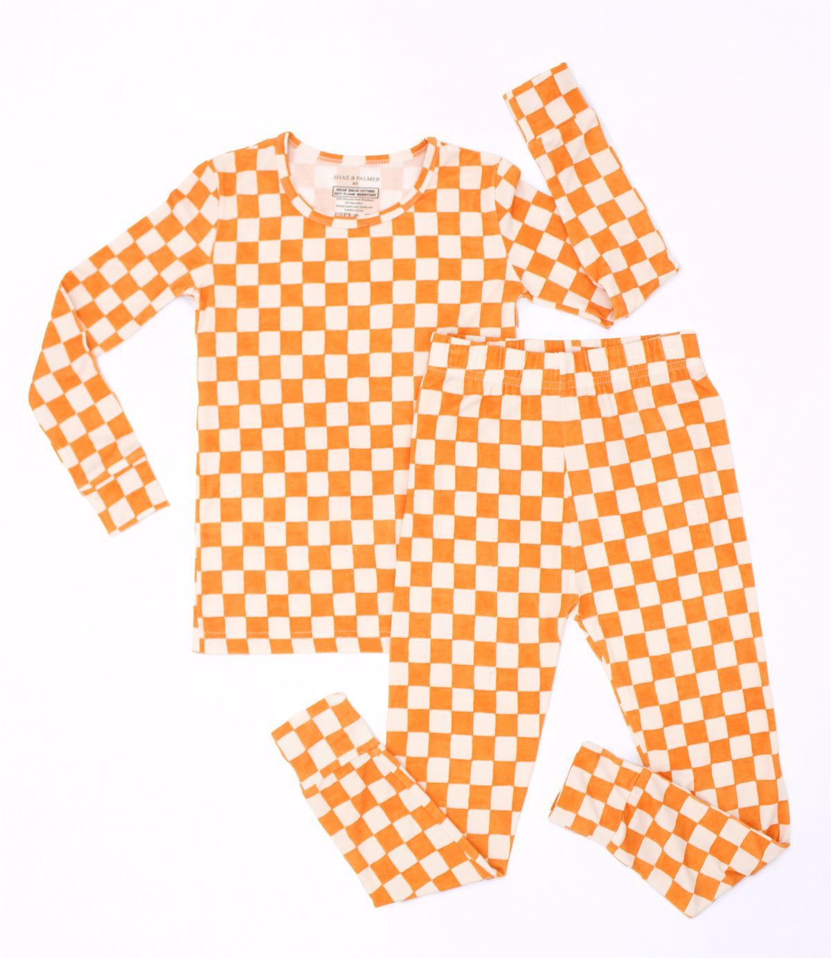 Orange and ivory Pumpkin Patch checkered big kids pajamas arranged in a flat lay, showcasing the long-sleeve top and matching pants