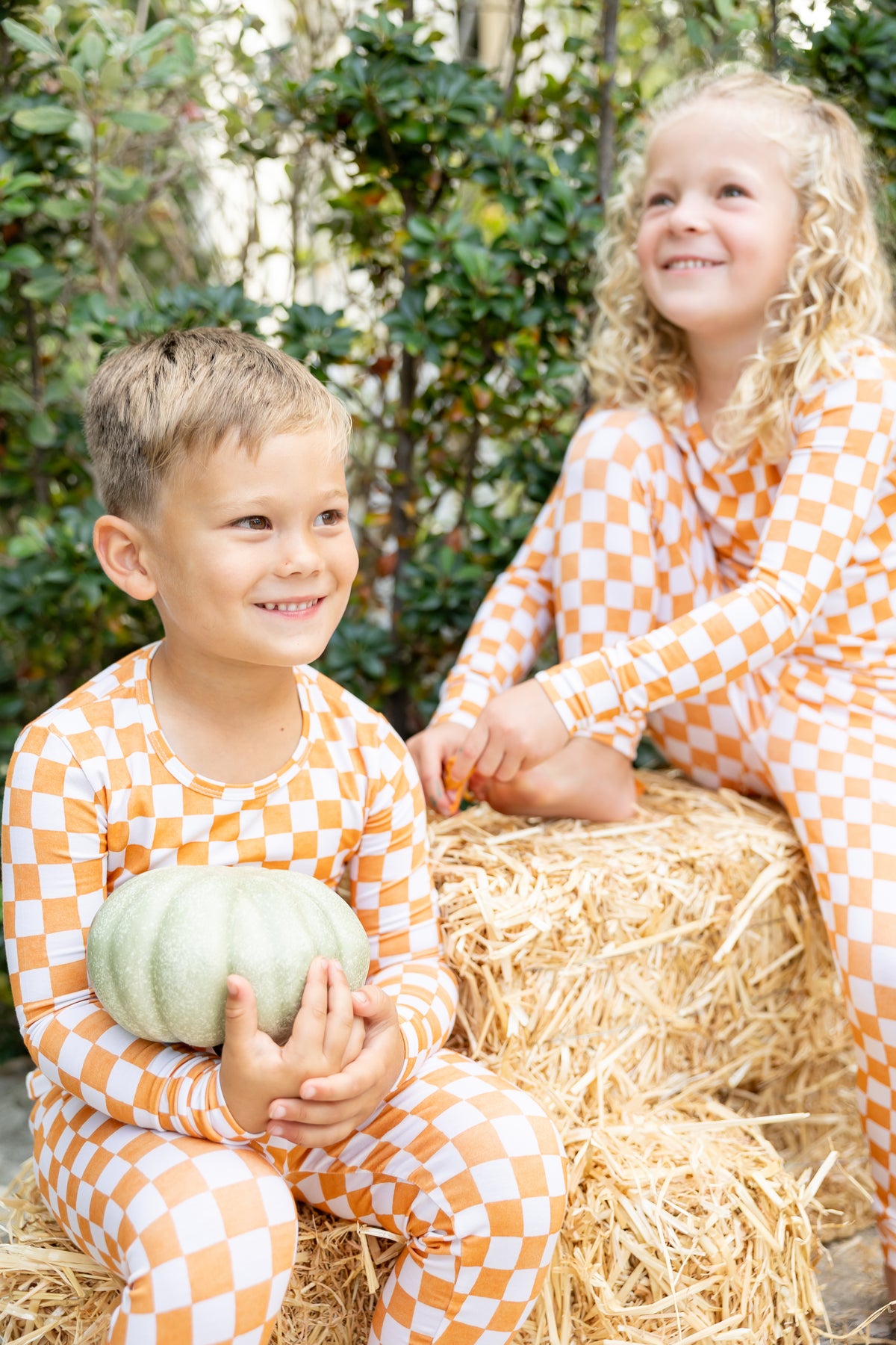 oddler in a two-piece Pumpkin Patch bamboo pajama set featuring an orange and ivory checkered print, perfect for cozy fall nights.