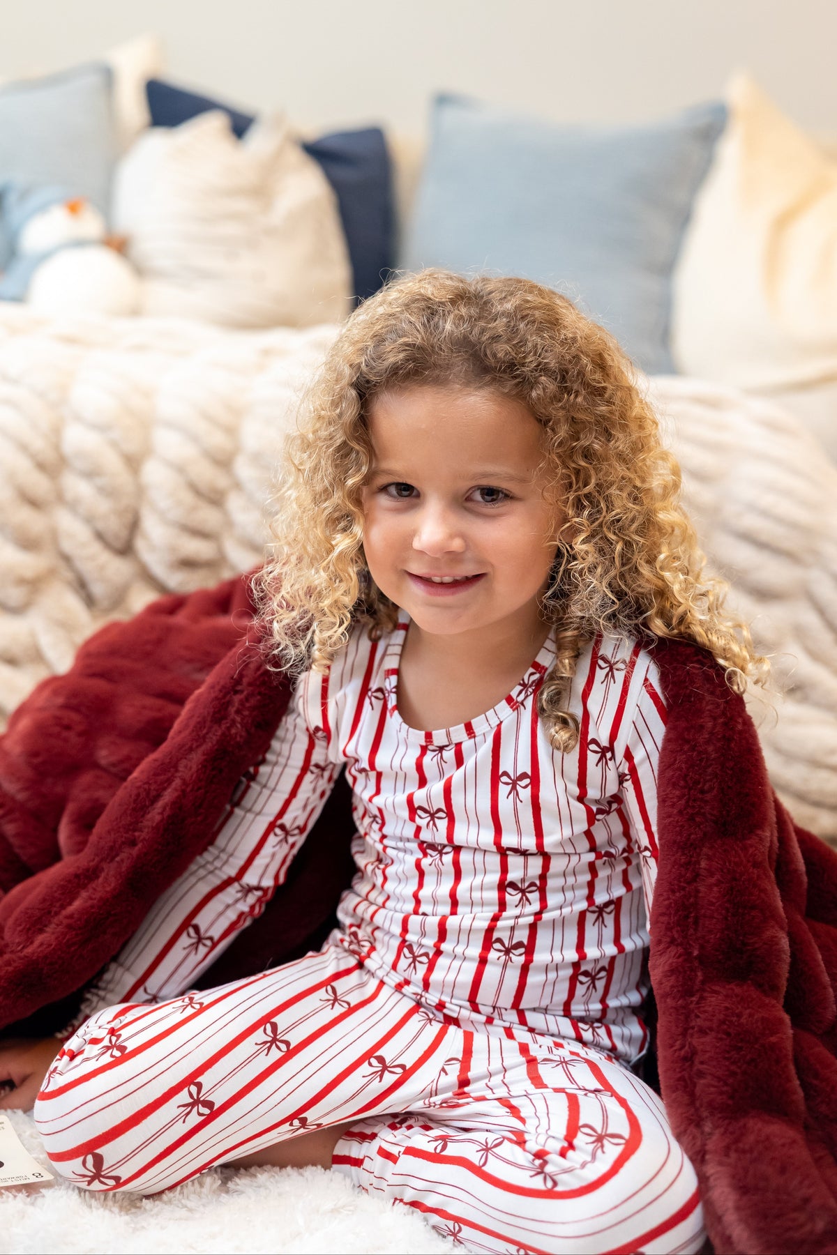 Girl wearing Ribbon Stripe bamboo pajamas by Shae & Palmer featuring classic red and white stripes with delicate bows. Soft, breathable Christmas pajamas perfect for holiday mornings, family photos, matching family pajama sets, and cozy winter nights.