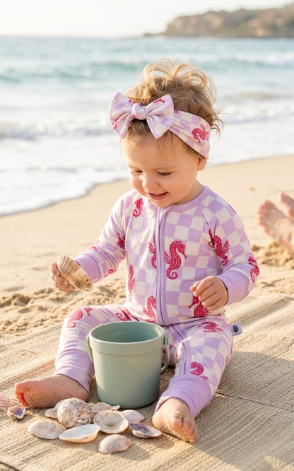 aby girl wearing Seahorse Splash bamboo pajamas featuring coral seahorses and coastal lavender checkerboard design, soft luxury sleepwear