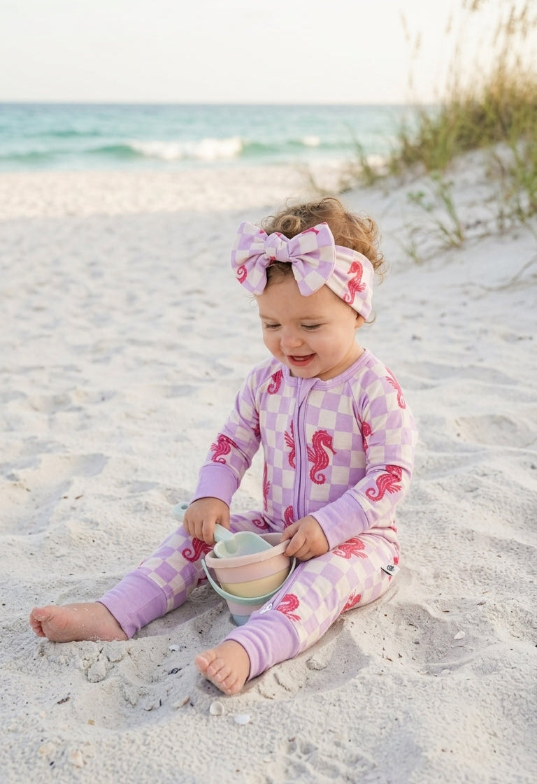 Infant in Seahorse Splash bamboo zipper romper with coral seahorses and lavender check pattern, buttery-soft breathable baby pajamas