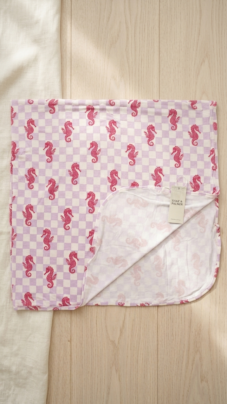 Close-up of Seahorse Splash bamboo blanket showing lavender checkered fabric with coral seahorse coastal design