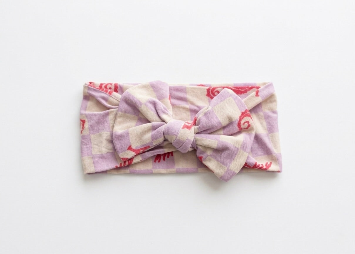 Seahorse Splash bamboo baby headband by Shae & Palmer featuring coral seahorses on a soft lavender checkerboard, ultra-soft, stretchy, and gentle on sensitive skin
