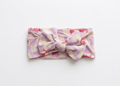 Seahorse Splash bamboo baby headband by Shae & Palmer featuring coral seahorses on a soft lavender checkerboard, ultra-soft, stretchy, and gentle on sensitive skin