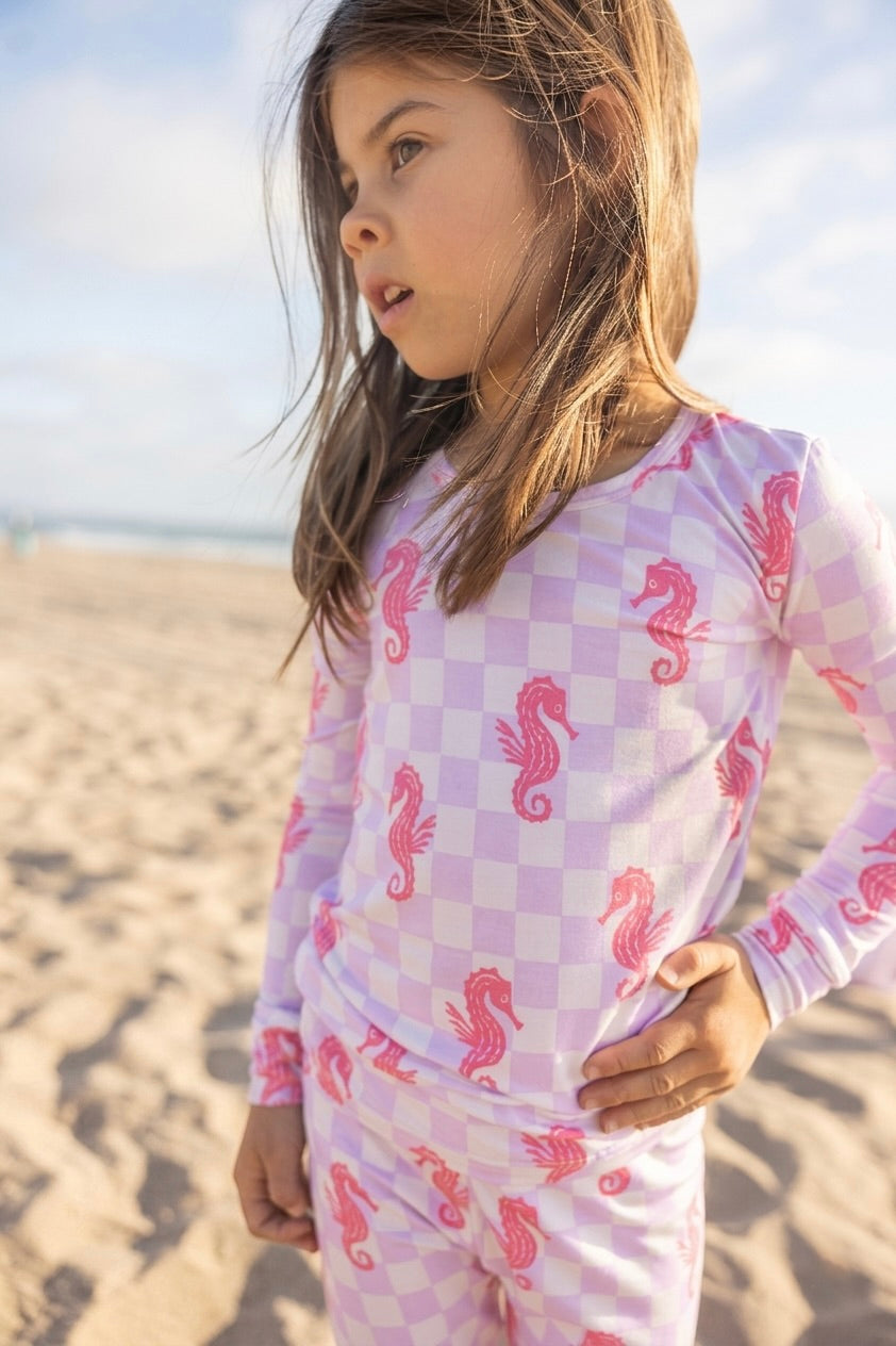 Big kids bamboo pajamas in the Seahorse Splash print featuring coral pink seahorses on a soft lavender checkerboard background by Shae & Palmer