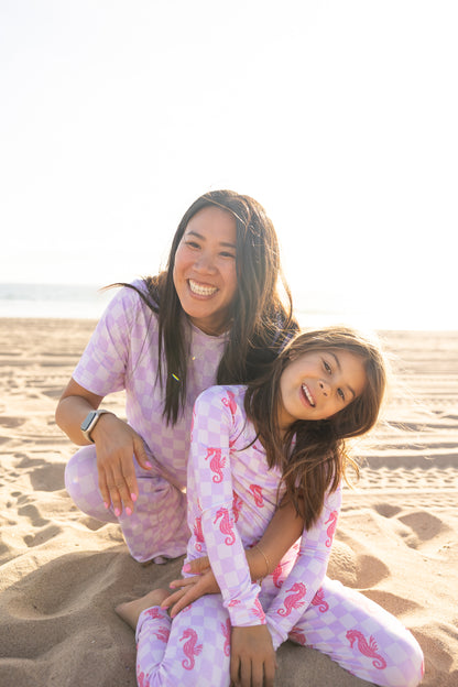 Mom and child wearing matching Seahorse Splash bamboo pajamas featuring coral pink seahorses on a soft lavender checkerboard print by Shae & Palmer