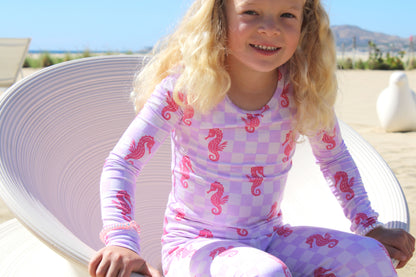 Close-up of Seahorse Splash toddler pajamas showing lavender checkered fabric with coral seahorse design detail