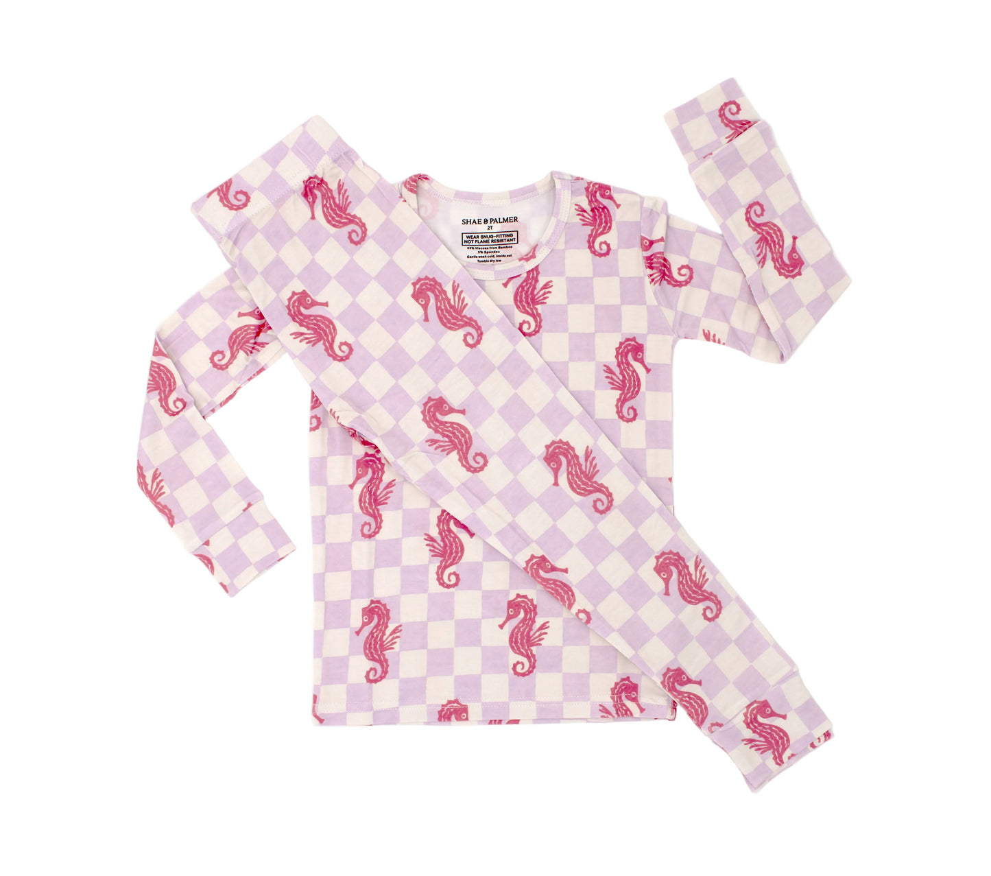 Toddler wearing Seahorse Splash bamboo pajamas with lavender checkered pattern and coral seahorse print front view