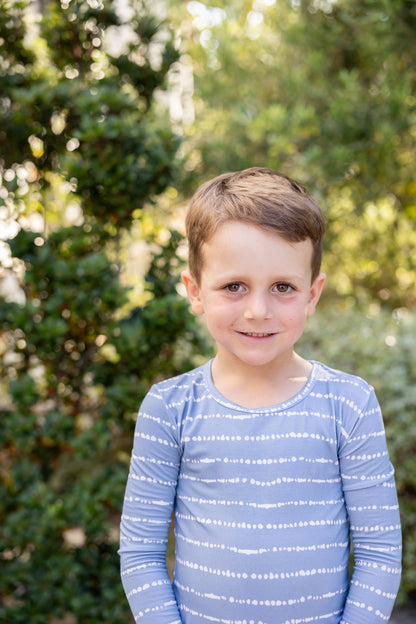 Big kid boy smiling in Blue Raspberry Stripe bamboo pajama set outdoors