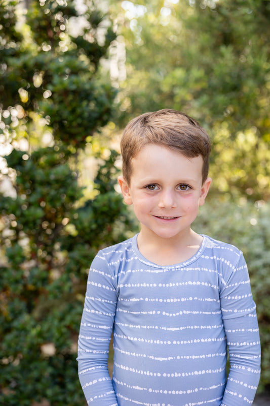 Big kid boy smiling in Blue Raspberry Stripe bamboo pajama set outdoors
