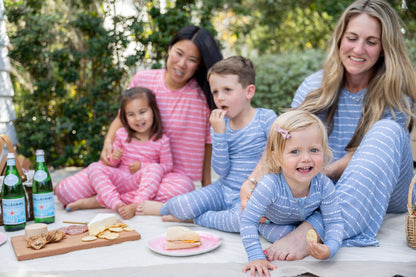 Moms and kids in matching Blue Raspberry Stripe bamboo pajamas and romper at a backyard picnic