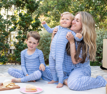 Mom and kids in matching Blue Raspberry Stripe bamboo pajamas sharing a picnic