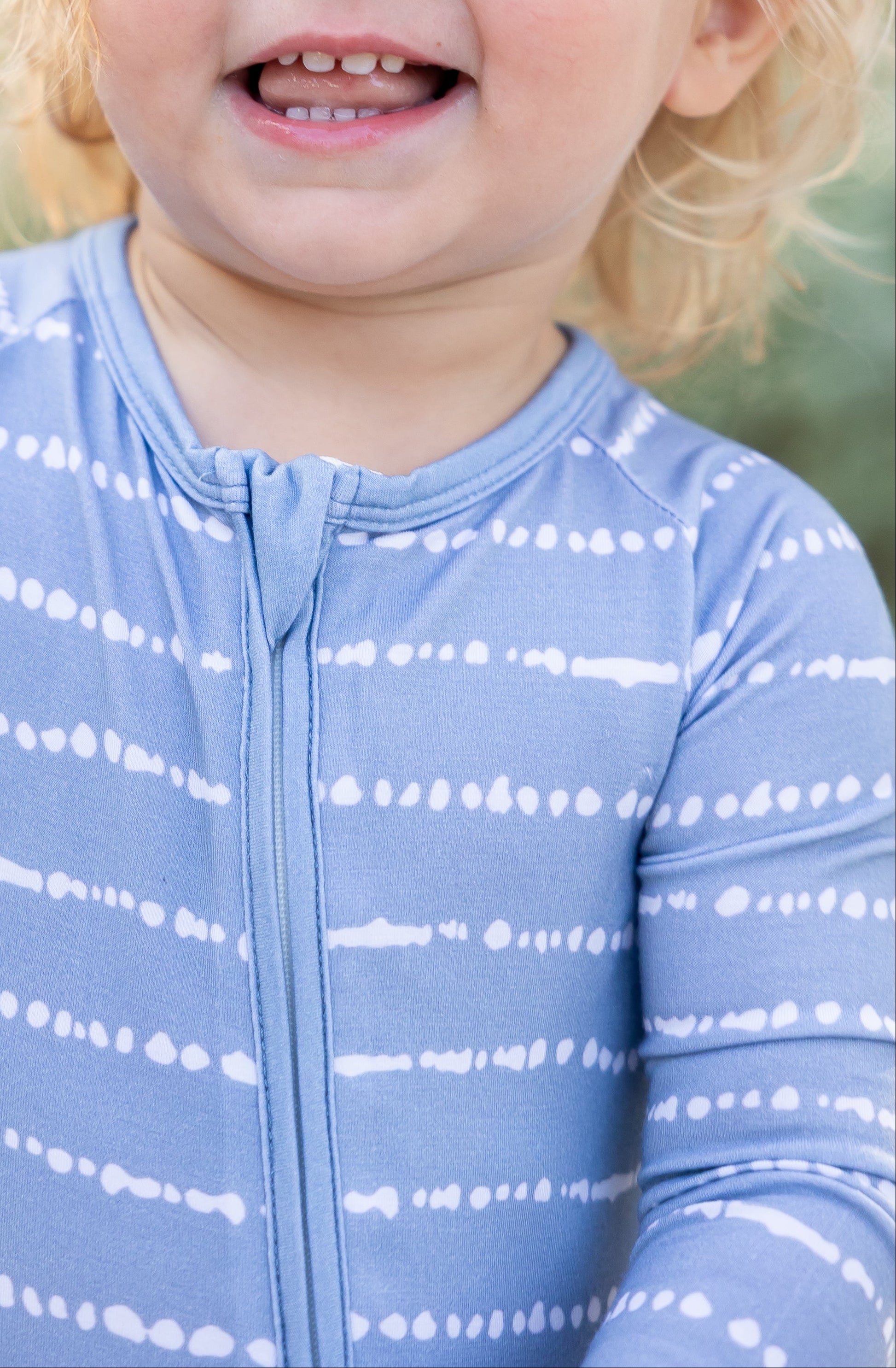 Close-up of toddler in Blue Raspberry Stripe bamboo zip romper with soft breathable fabric