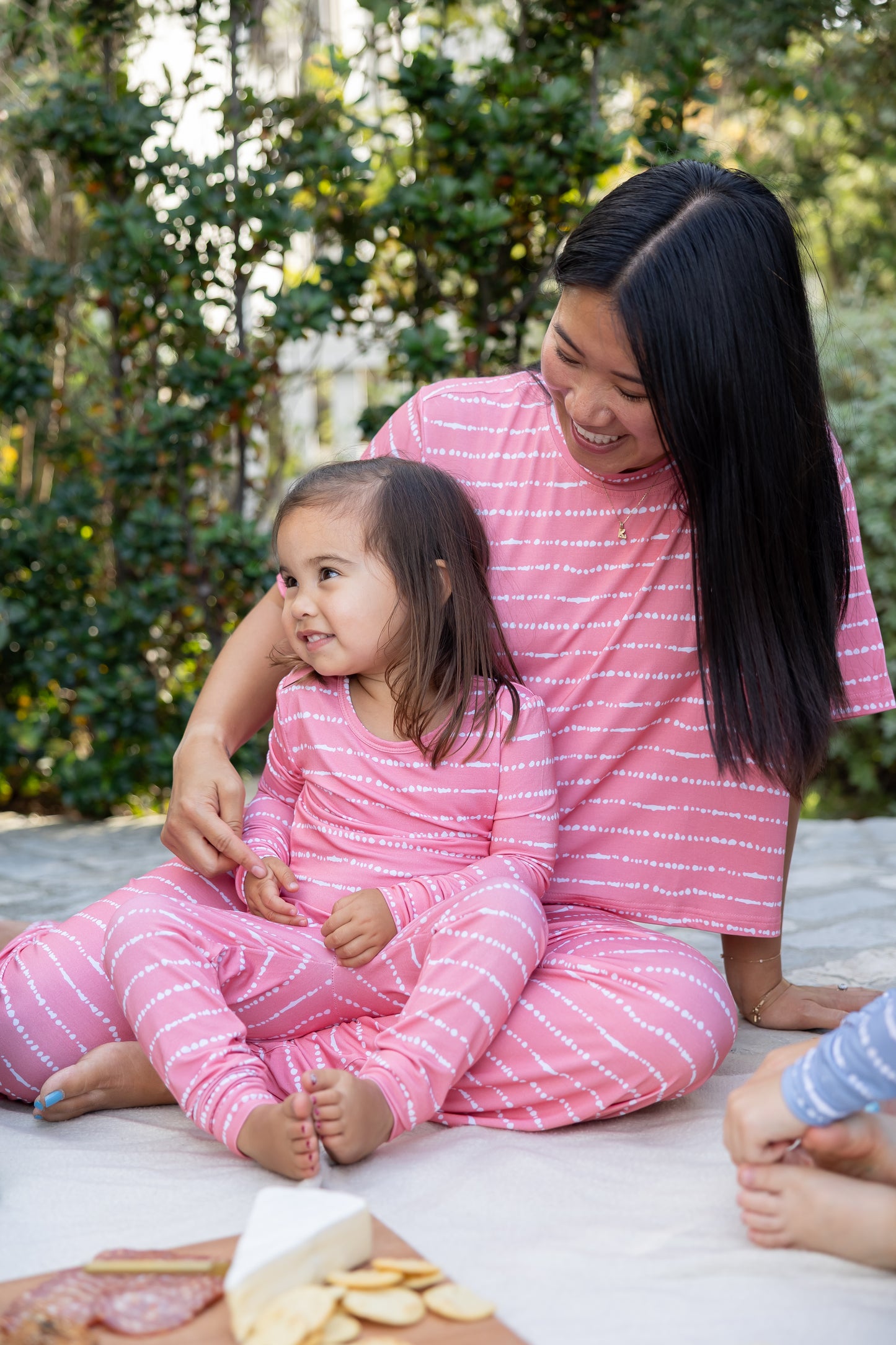 Mom and toddler girl in matching Watermelon Blush Stripe bamboo pajamas at a picnic