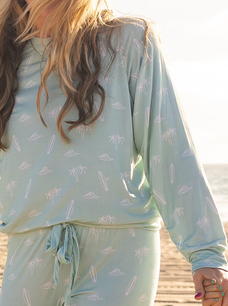Women’s Surfside Dreams bamboo pajama set by Shae & Palmer featuring surfboards, palm trees, and ocean-inspired details in soft seafoam hues.