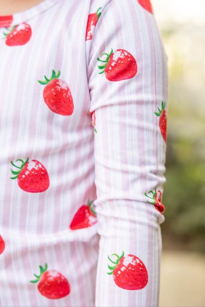 Close-up of Strawberry Fields pink striped bamboo pajamas, showing soft, breathable fabric with hand-illustrated strawberry print for babies and toddlers