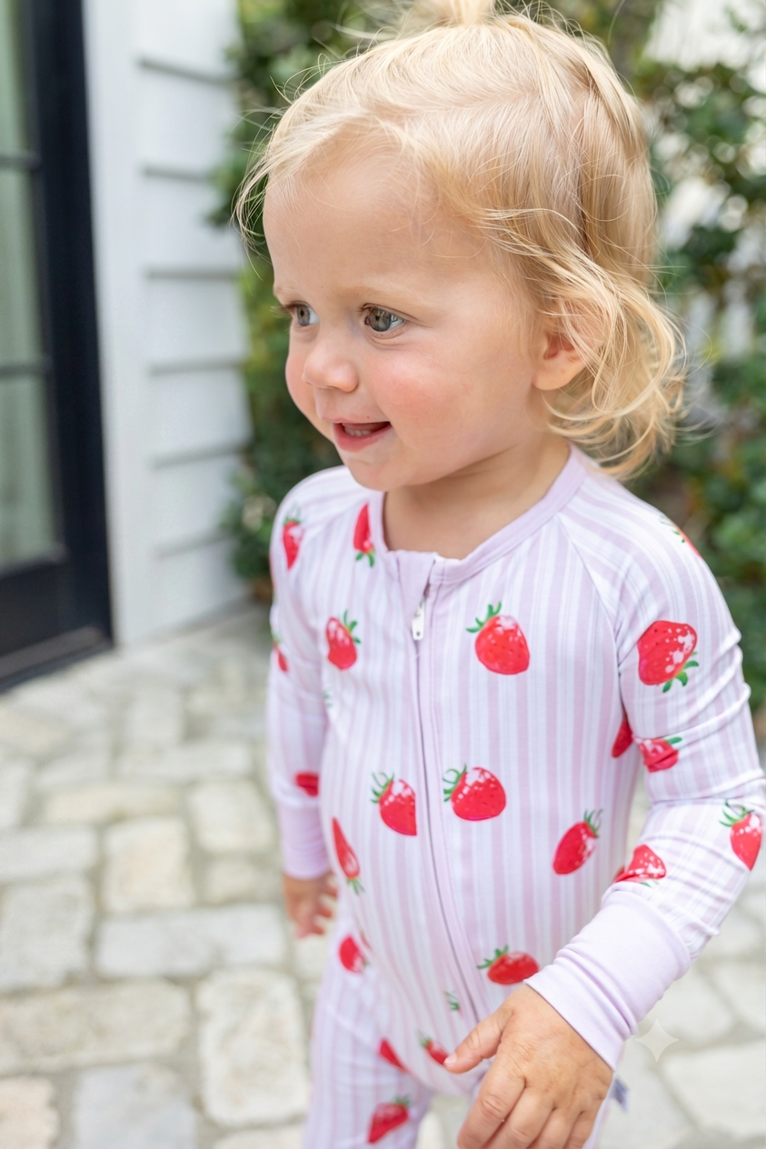 Toddler girl wearing Strawberry Fields pink striped bamboo zip pajamas, a breathable, temperature-regulating sleepwear set gentle on sensitive skin.