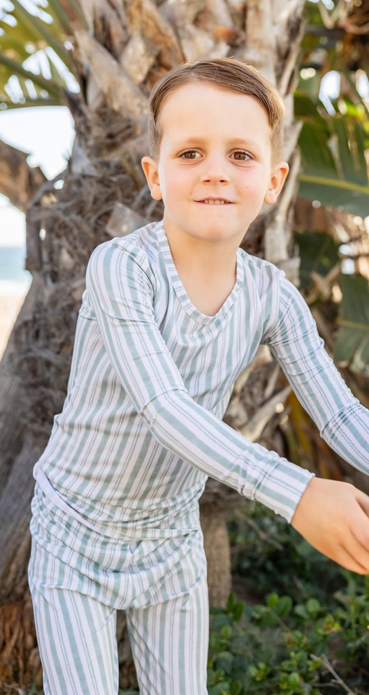 Big kid wearing Shae & Palmer Studio Stripe Green Haze bamboo pajamas featuring muted green painterly stripes and ultra-soft breathable bamboo fabric.
