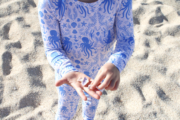 Toddler wearing Shae & Palmer Hidden Ocean Treasures bamboo pajama set with octopus, shells, and anchor print.